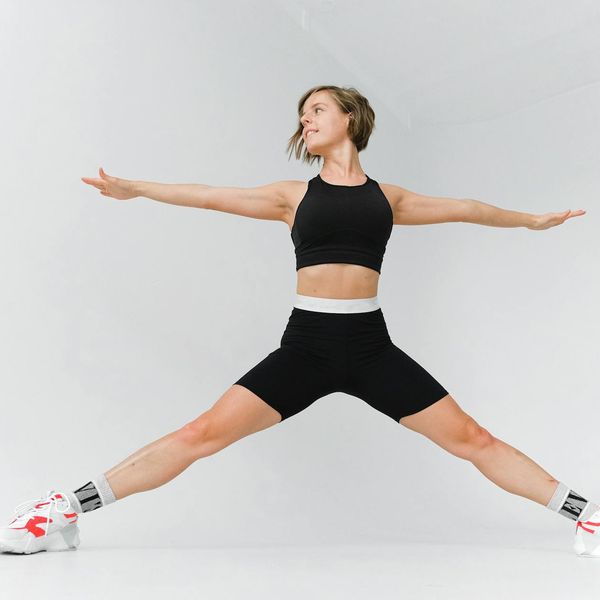 Woman performing an energetic yoga pose against a dark background.
